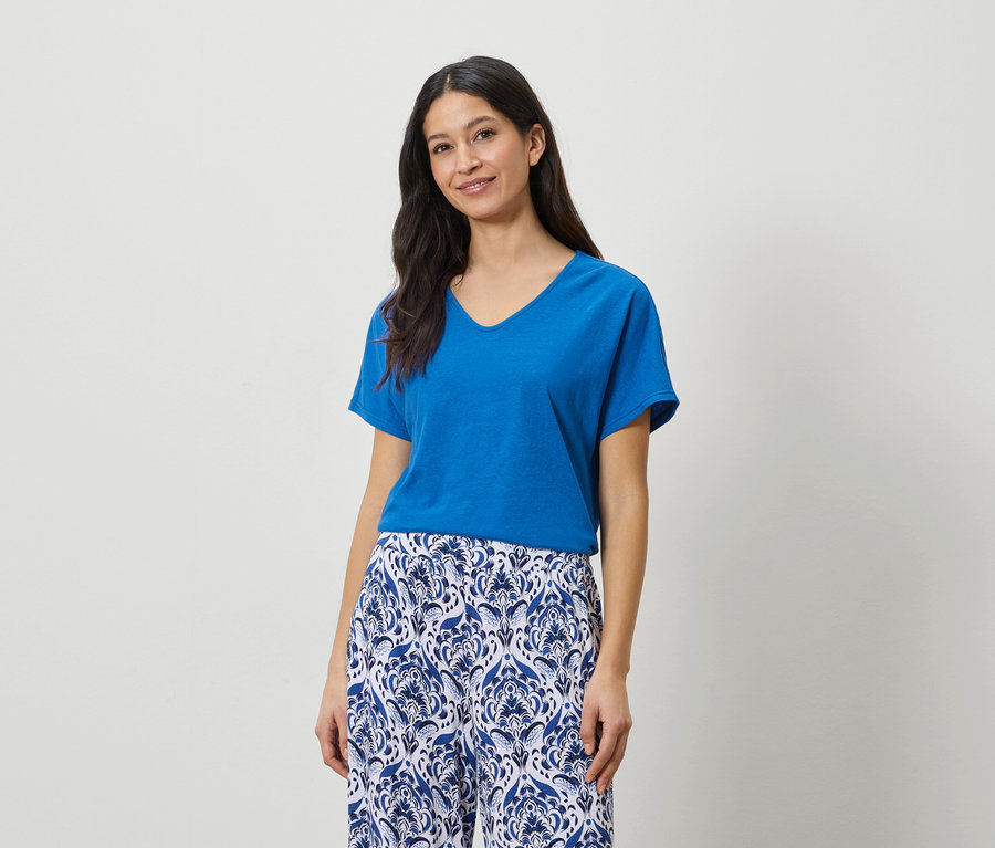 Une femme porte un t-shirt bleu et un pantalon à motifs bleus et blancs.