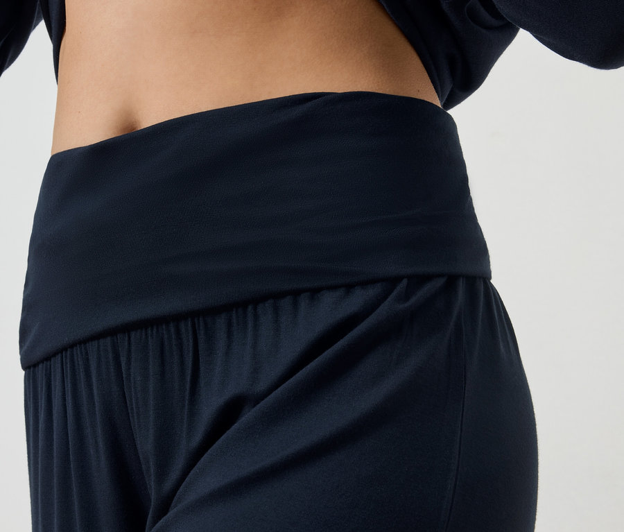 Gros plan d'une femme portant une tenue de yoga bleu marine, composée d'un pantalon et d'un haut à manches longues.