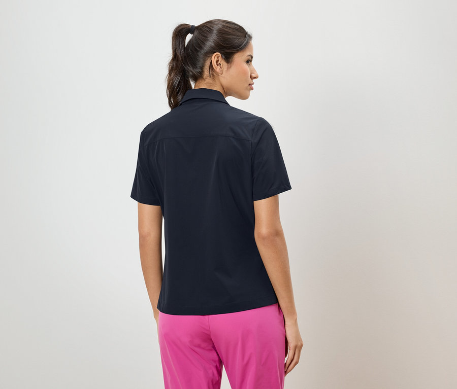 Vue arrière d'une femme avec une queue de cheval portant une chemise bleu marine et un pantalon rose.