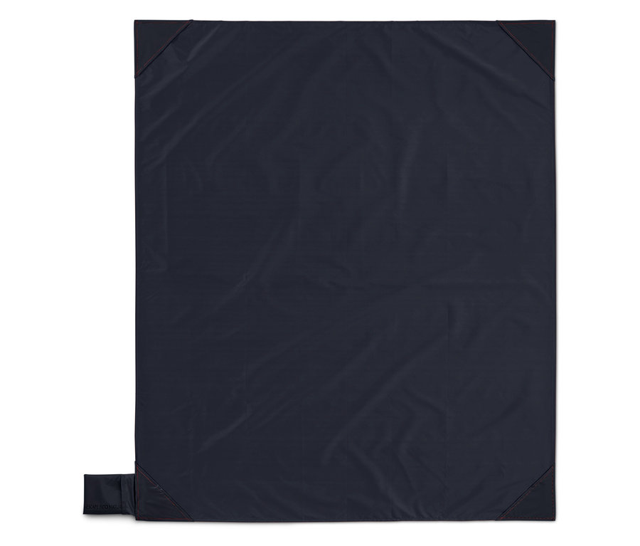 Couverture bleu foncé avec des coutures rouges aux coins, étalée à plat.