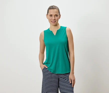 Femme portant un haut vert sans manches et un pantalon rayé.