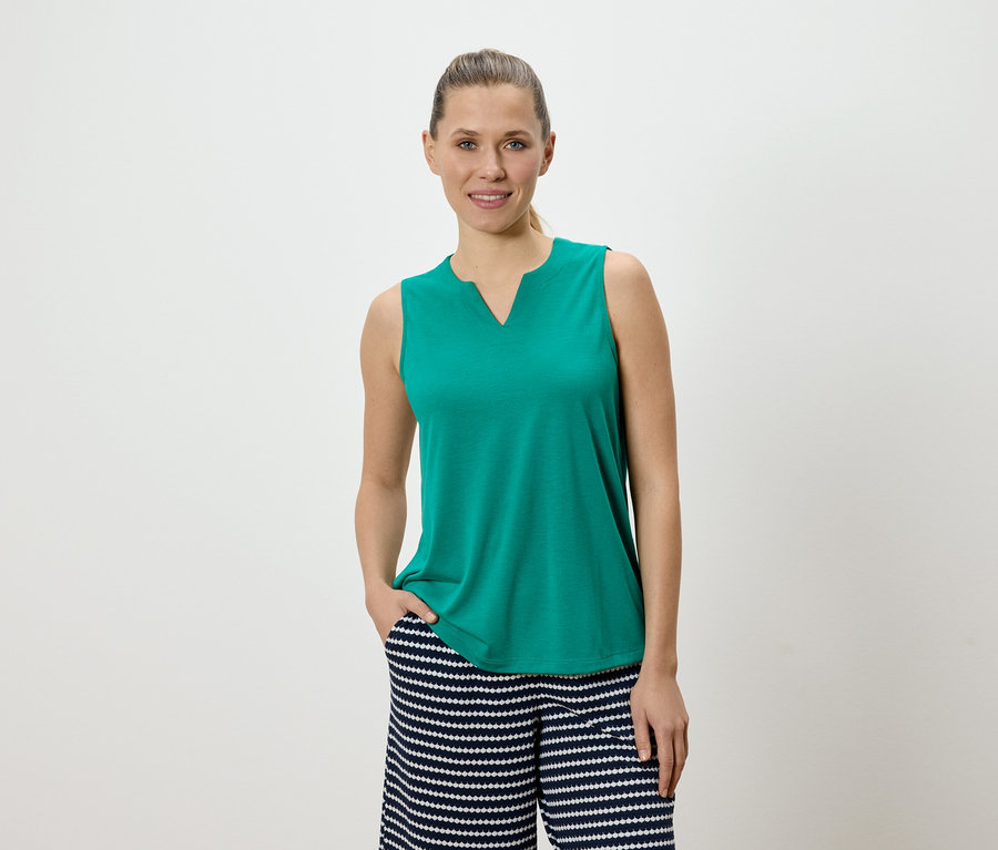 Femme portant un haut vert sans manches et un pantalon rayé.