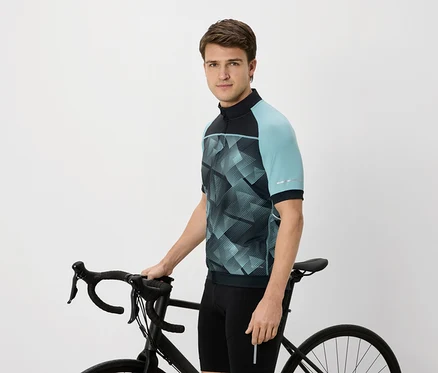Homme en maillot de cyclisme avec des manches bleu-vert tenant un vélo noir.