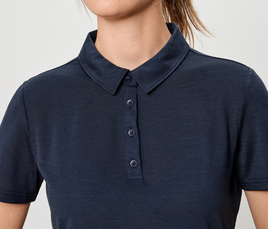 Gros plan d'une femme portant un polo bleu marine boutonné.