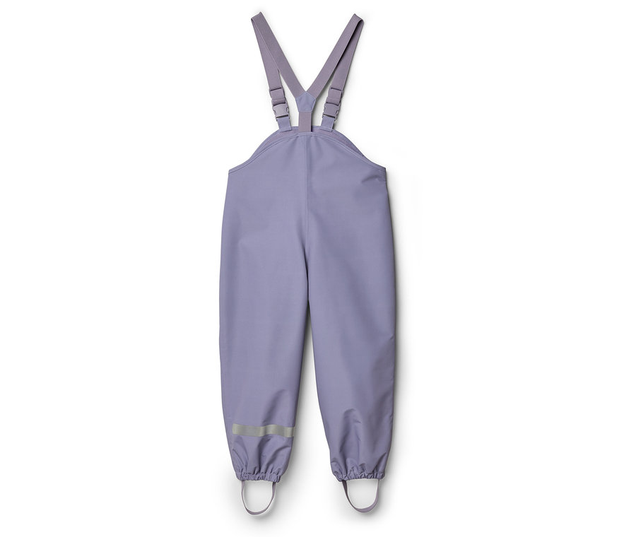 Un pantalon de pluie lilas à bretelles est posé sur un fond blanc.