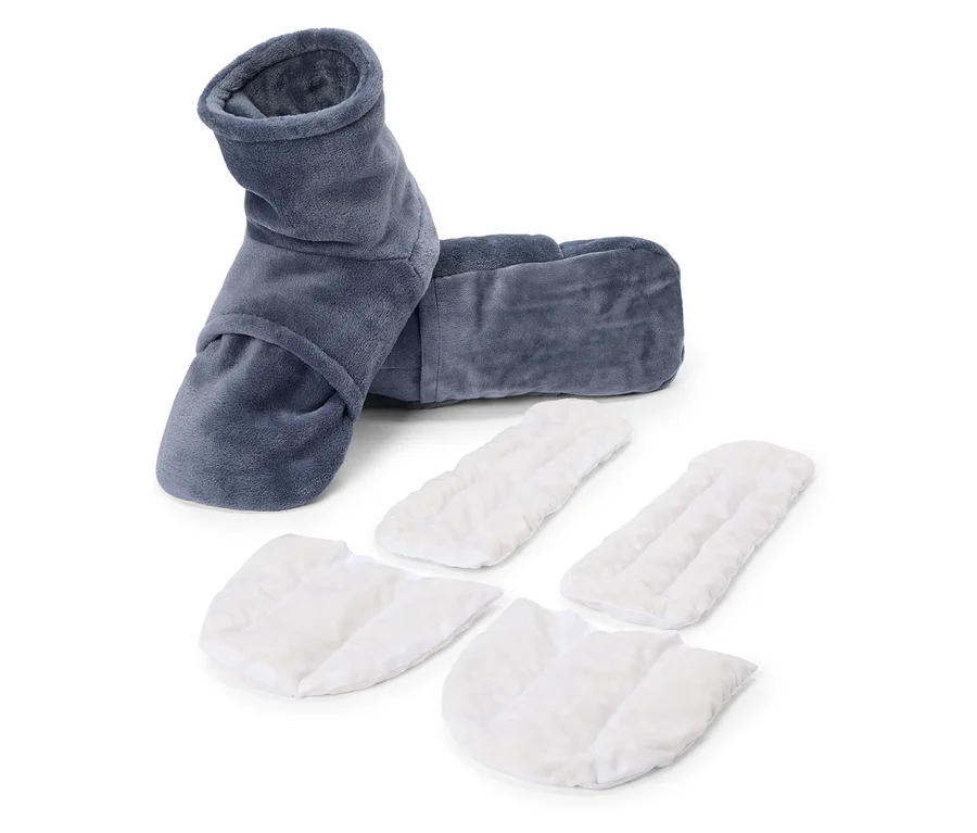Une paire de chauffe-pieds gris et veloutés avec quatre semelles intérieures blanches et lavables posées sur un fond blanc.