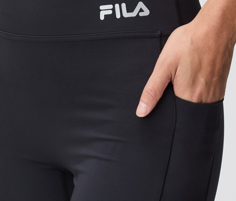 Gros plan d'un legging Fila noir avec une main dans la poche.