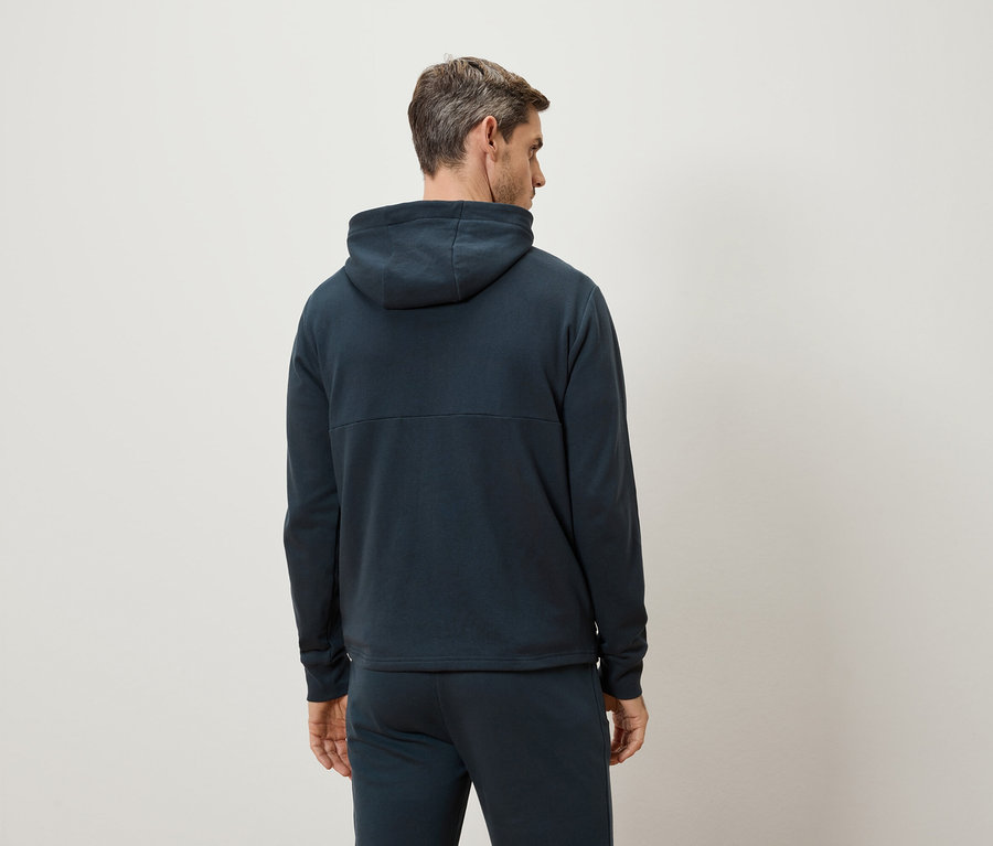 Homme vu de dos portant un sweat à capuche bleu foncé et un pantalon de survêtement.