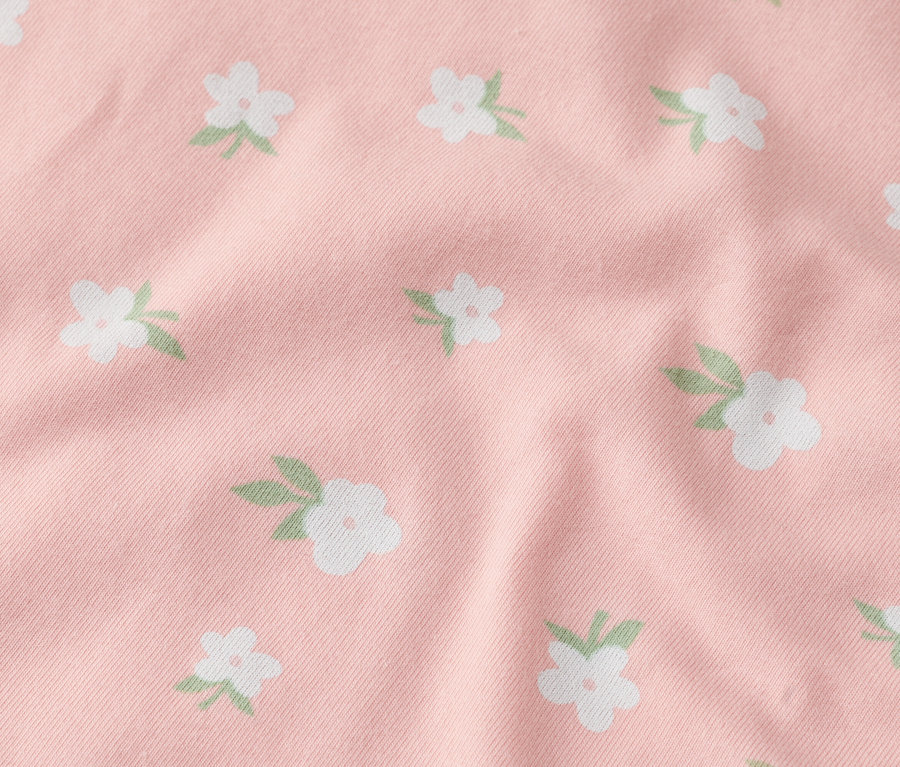 Gros plan d'un tissu rose avec des fleurs blanches.