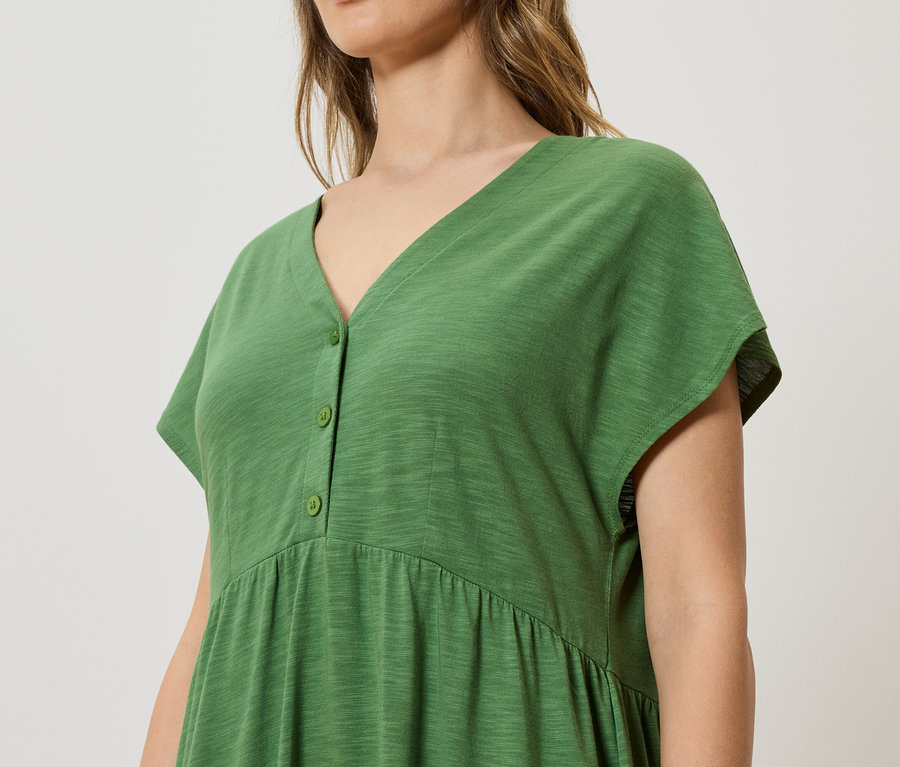 Gros plan d'une femme portant une robe verte boutonnée.