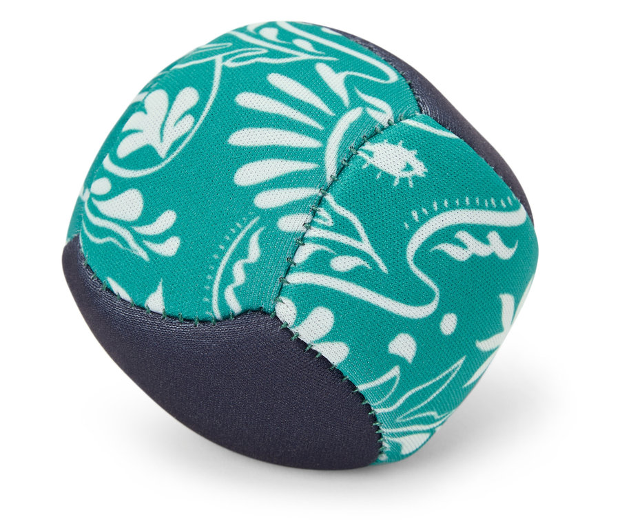 Une balle de jonglage turquoise et bleue avec un motif blanc repose sur le sol.