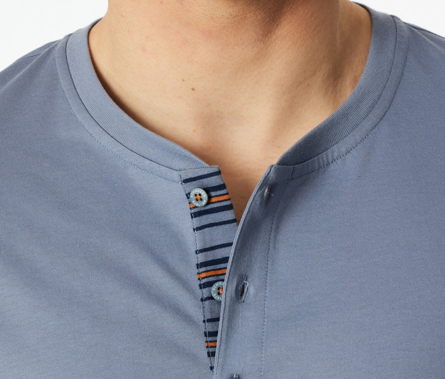 Gros plan d'un homme portant un polo bleu avec des boutons et des détails rayés.