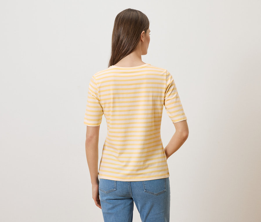 Vue arrière d'une femme aux longs cheveux bruns portant un t-shirt rayé jaune et blanc et un jean.