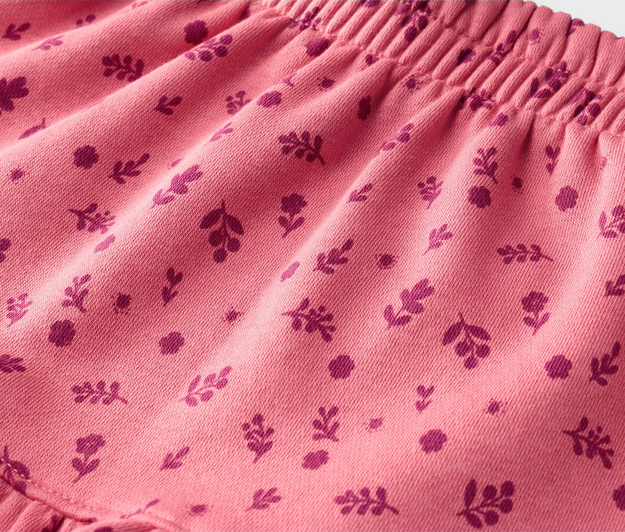 Gros plan d'un tissu rose avec un motif de petites fleurs et feuilles rose foncé.