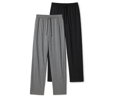 Deux pantalons de survêtement, un gris et un noir, sont posés à plat. Les deux ont une taille élastique avec un cordon de serrage.