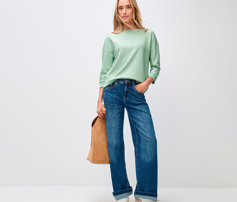 Femme en jean et t-shirt Street One avec détails côtelés, vert sauge, avec un sac marron.