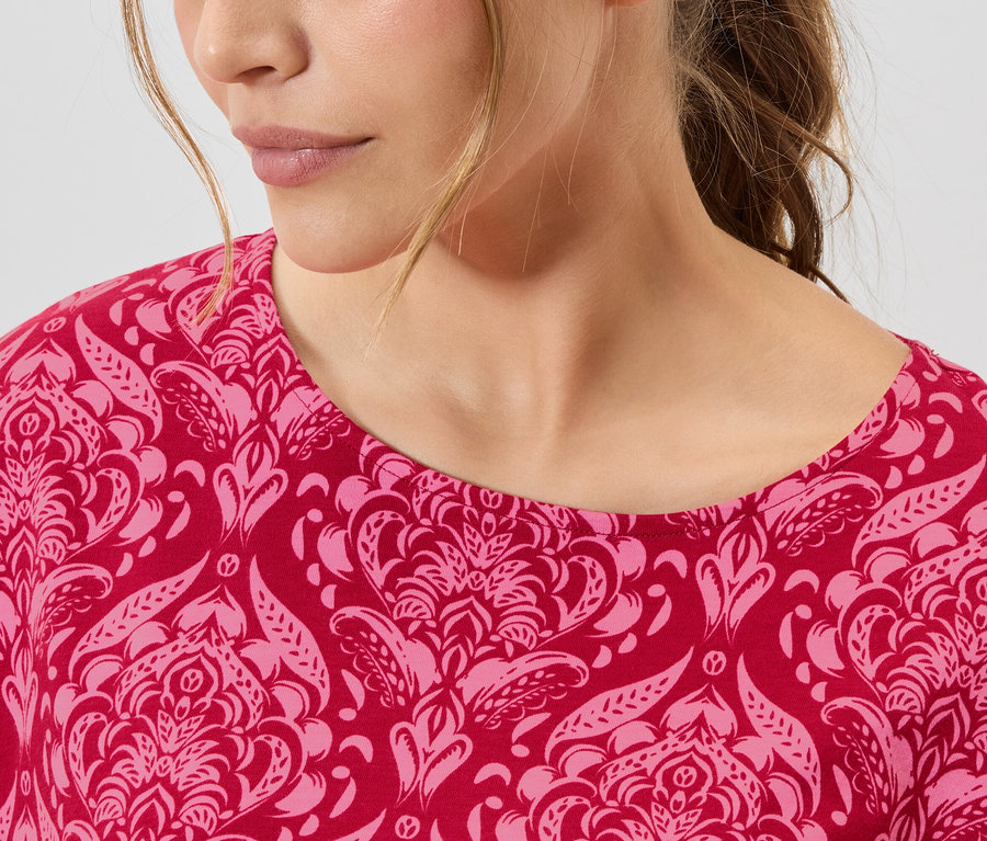Gros plan d'une femme portant un haut à motifs rose et rouge.