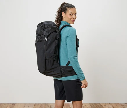 Femme avec un sac à dos noir sur les épaules, regardant par-dessus son épaule.