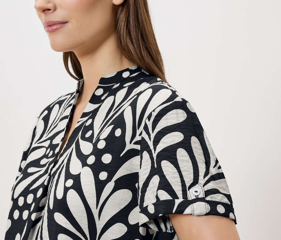Femme portant un chemisier noir et blanc à motif de feuilles.