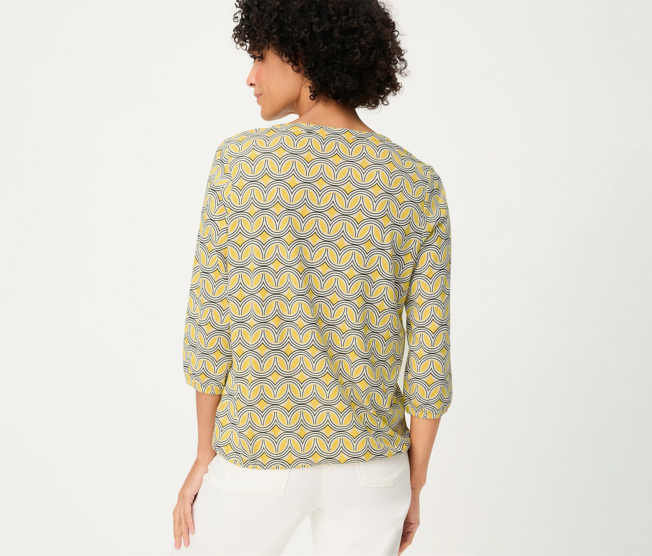 Femme de dos portant un chemisier Olsen 3/4 à motif jaune et un pantalon blanc.