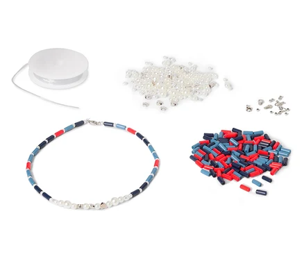 Un collier avec des perles bleues, rouges et blanches est posé à côté d'une bobine, de perles blanches et de perles cylindriques rouges et bleues.