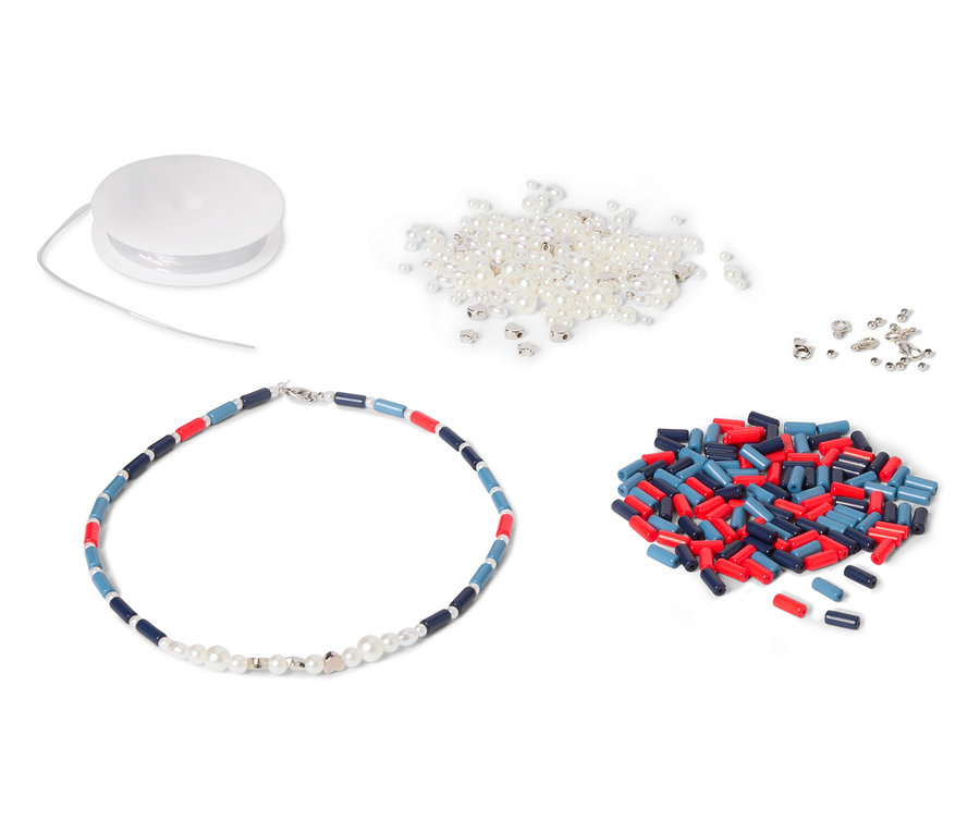 Un collier avec des perles bleues, rouges et blanches est posé à côté d'une bobine, de perles blanches et de perles cylindriques rouges et bleues.