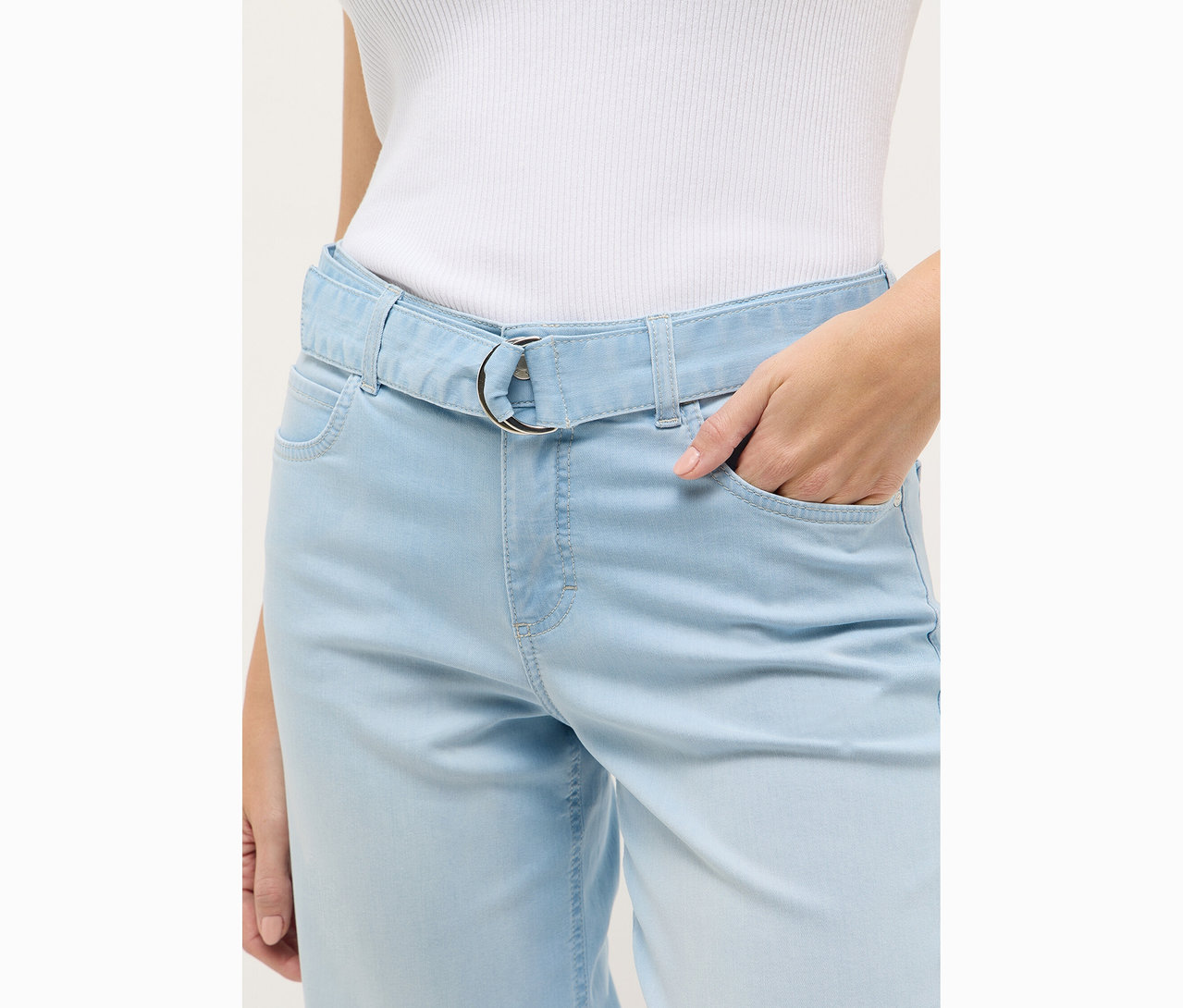Une femme porte un jean Angels Denim « Linn City » cropped, bleached blue. Sa main est dans sa poche.