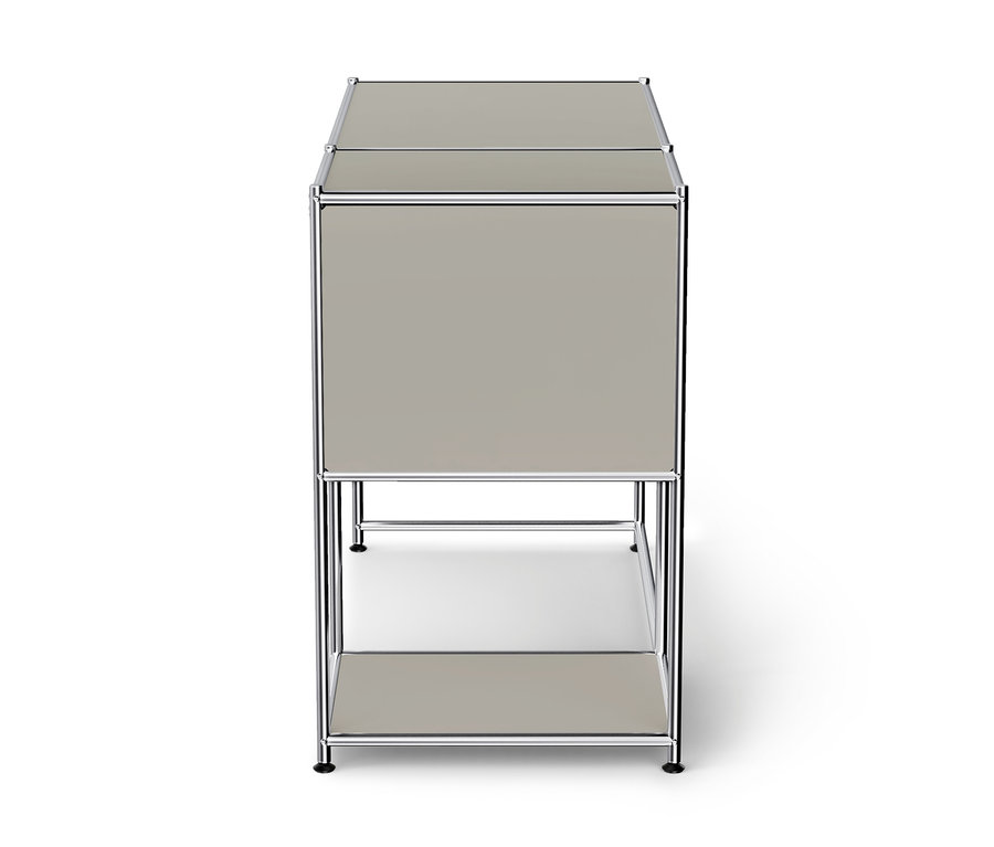 Meuble de rangement modulaire gris clair avec cadre chromé, comprenant une section supérieure fermée et une étagère inférieure ouverte, sur fond blanc.
