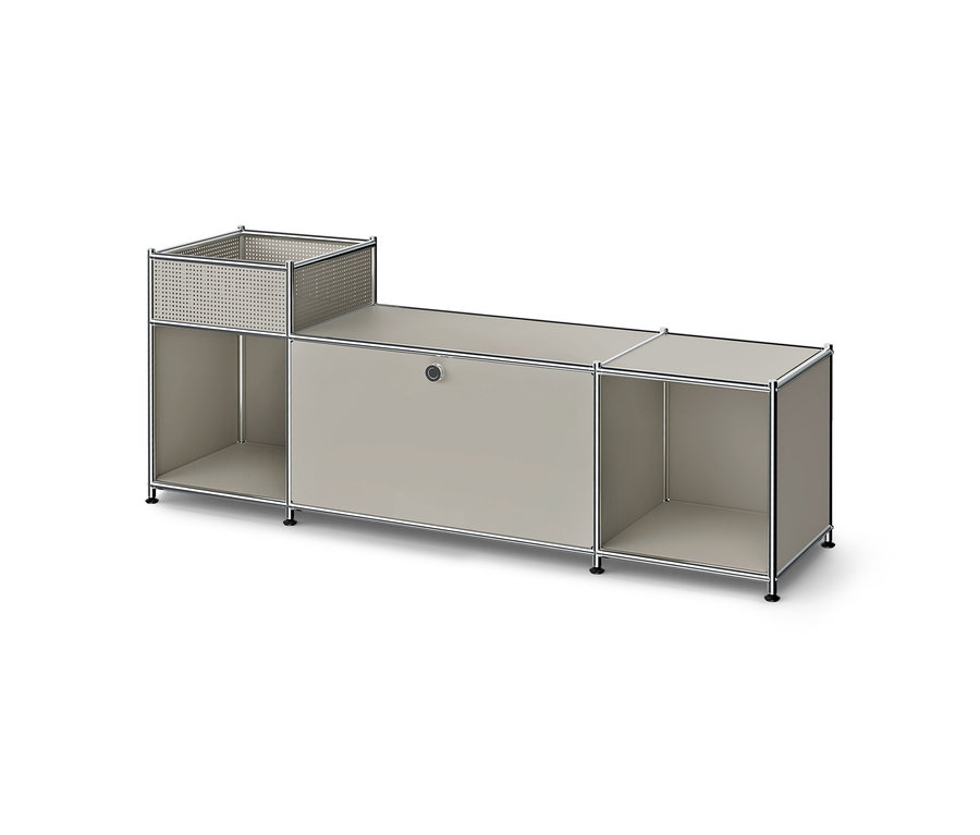 Meuble bas modulaire avec cadre métallique et panneaux gris clair. Il comprend un panier perforé sur une étagère ouverte à gauche, un compartiment fermé au centre et une étagère ouverte à droite.