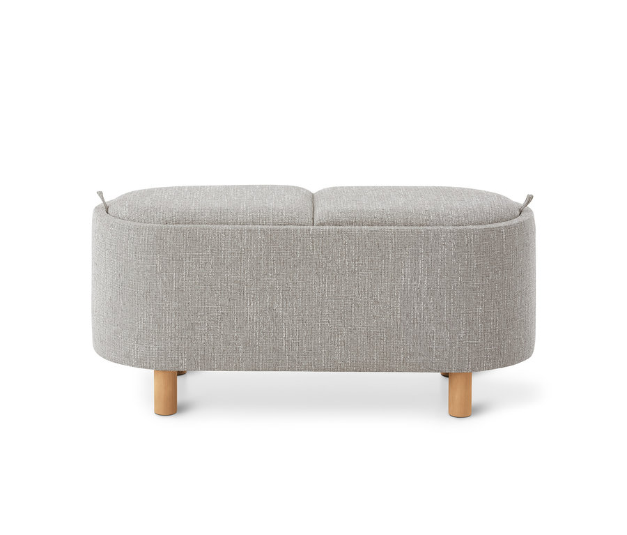 Banc de rangement rembourré gris clair aux coins arrondis, avec couvercle en deux parties, boucles en tissu et quatre pieds en bois clair.