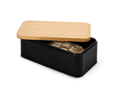 Un pain de campagne est posé dans une boîte à pain noire avec un couvercle en bois marron clair partiellement ouvert.