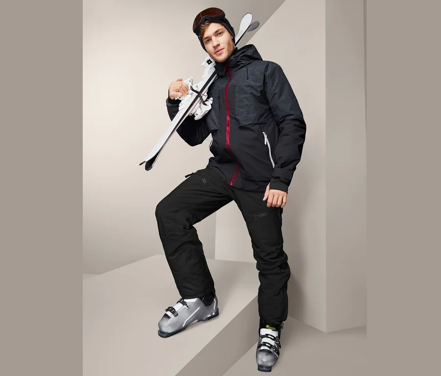 Homme en veste de ski « High-End » avec des skis et des chaussures de ski.