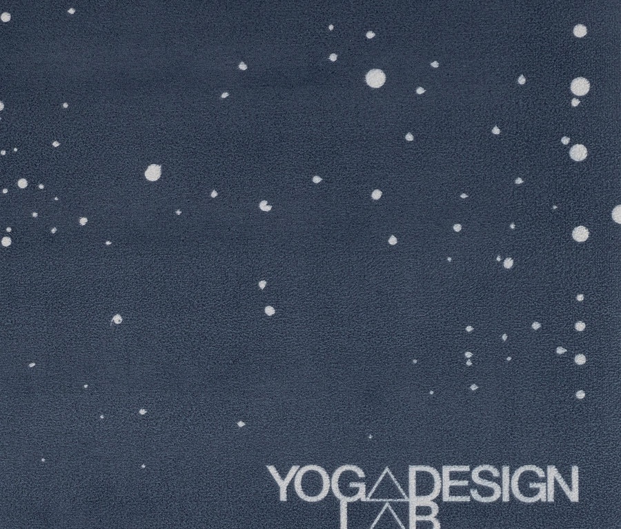 Gros plan d'un tapis de yoga bleu foncé avec des points blancs et le logo Yoga Design Lab.