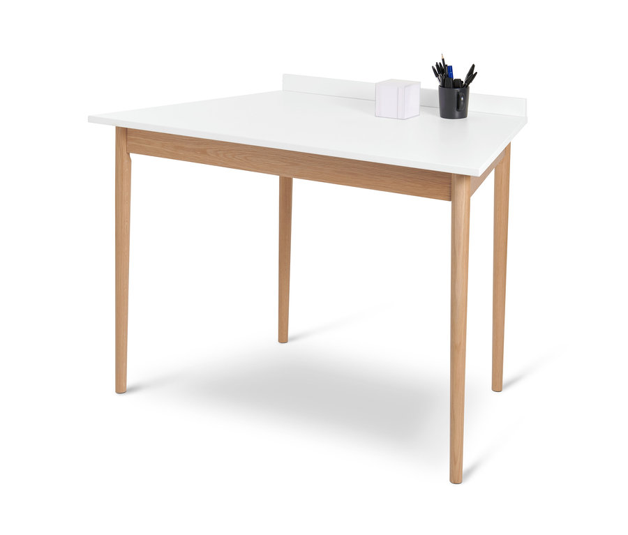 Bureau blanc en forme de trapèze avec quatre pieds en bois et une tasse noire avec des articles de papeterie.