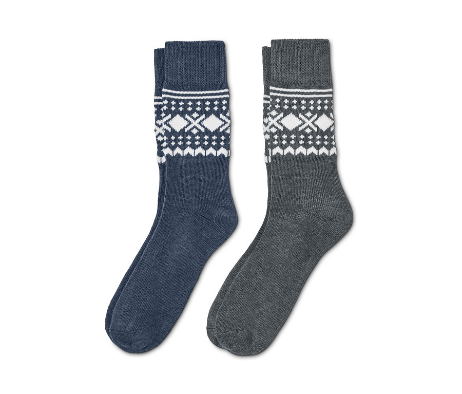 Deux paires de chaussettes jacquard, une bleue avec un motif blanc, une grise avec un motif blanc.