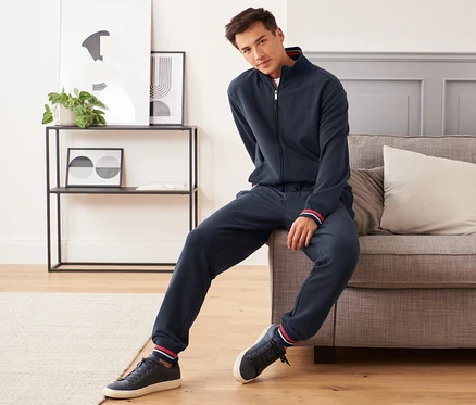 Homme assis sur un canapé portant un pantalon de jogging.