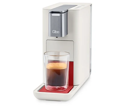 Machine à café Qbo ESSENTIAL Bright Coral avec une tasse de café.