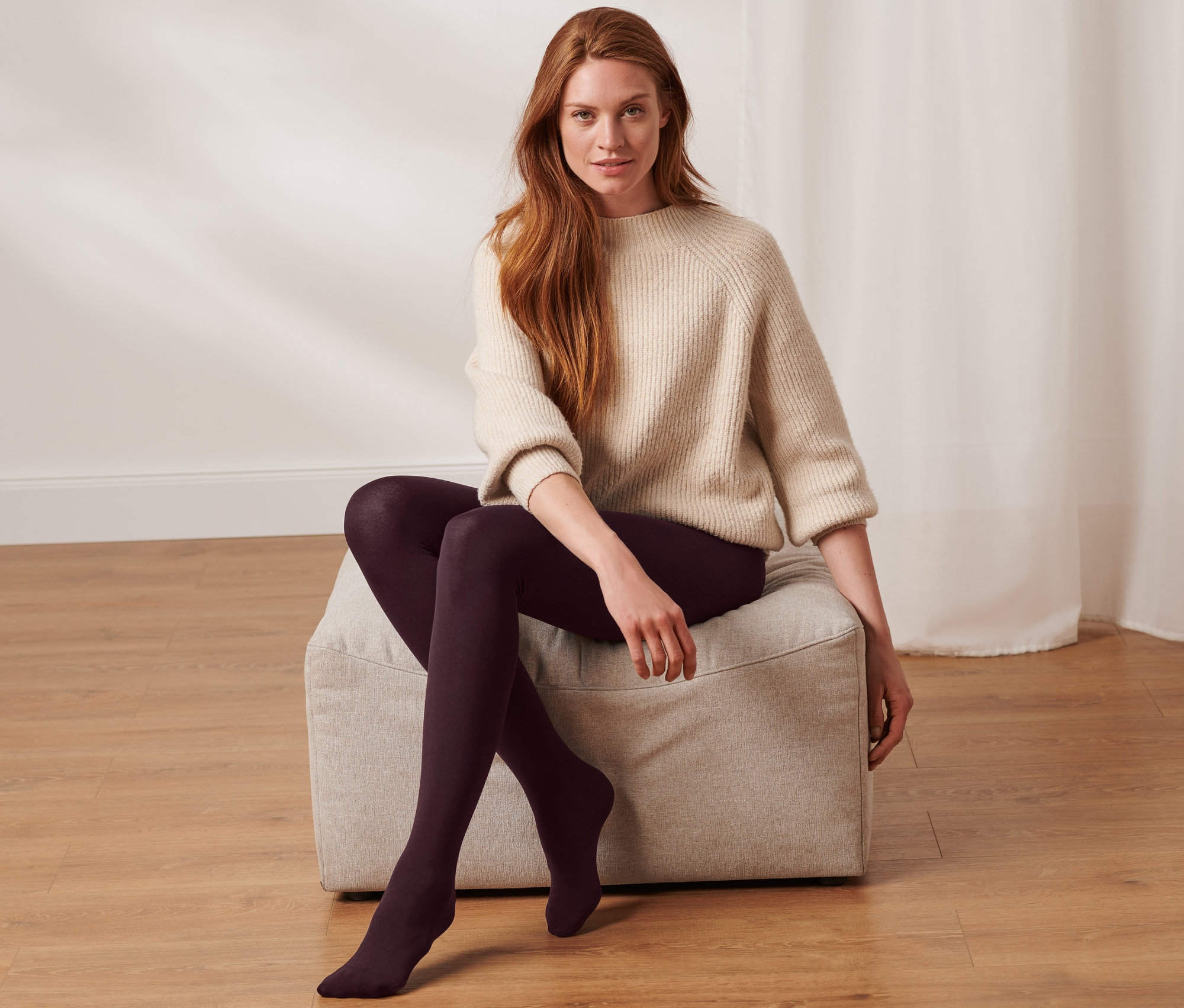 Une femme est assise sur un tabouret et porte des collants thermiques.