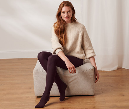 Une femme est assise sur un tabouret et porte des collants thermiques.