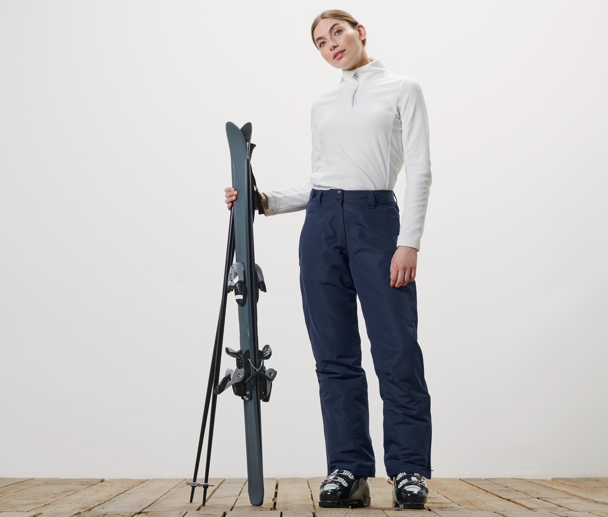 Femme tenant des skis et portant un pantalon de ski.