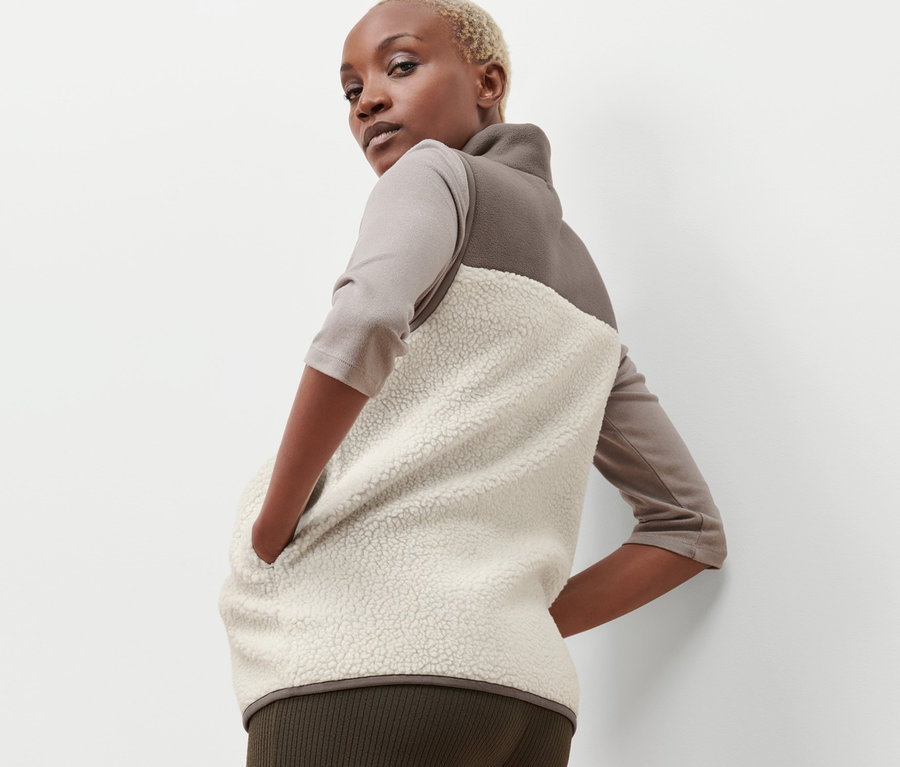Femme posant dans un gilet sans manches en peluche beige et marron.
