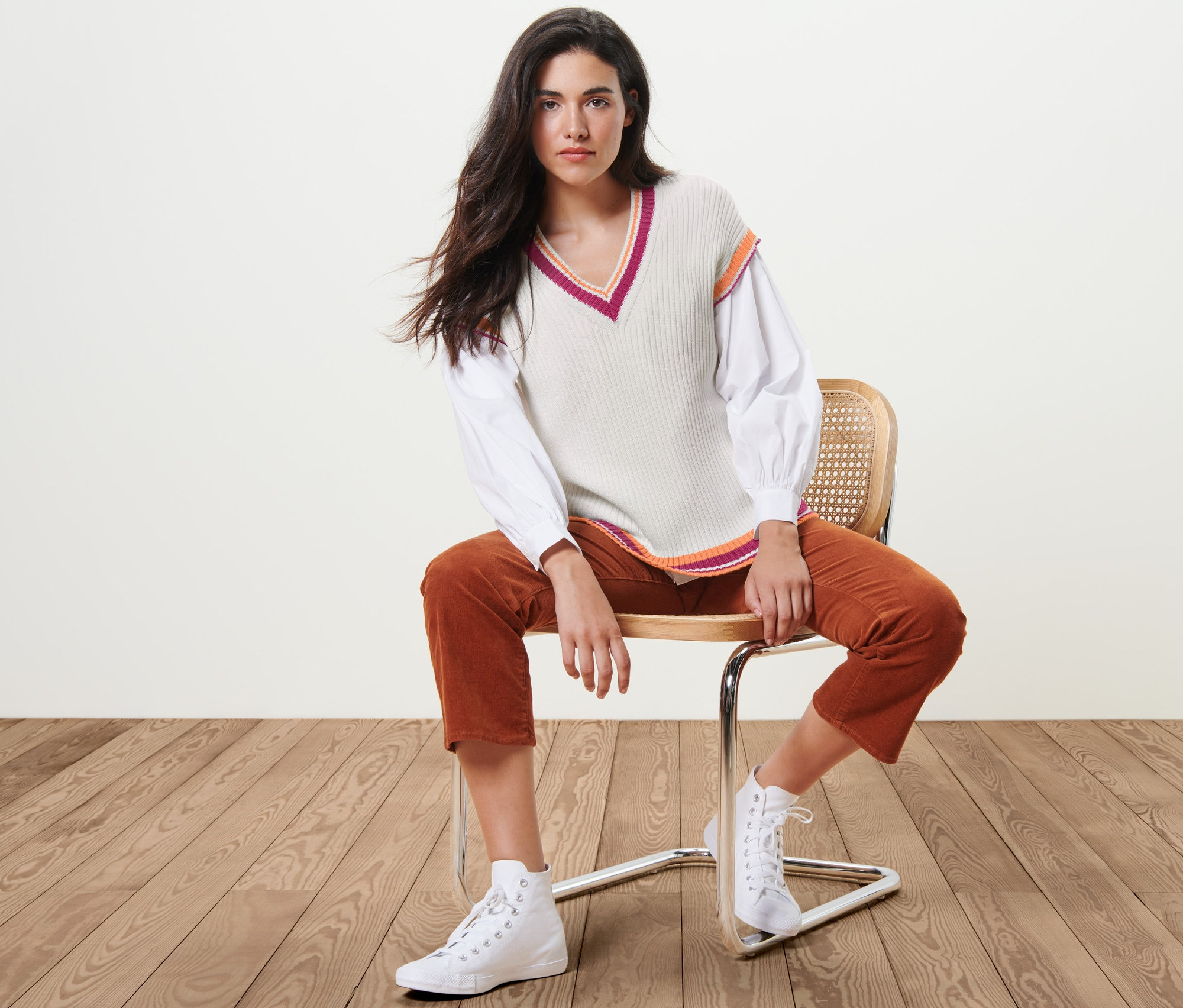 Femme assise sur une chaise portant un pull sans manches en maille.