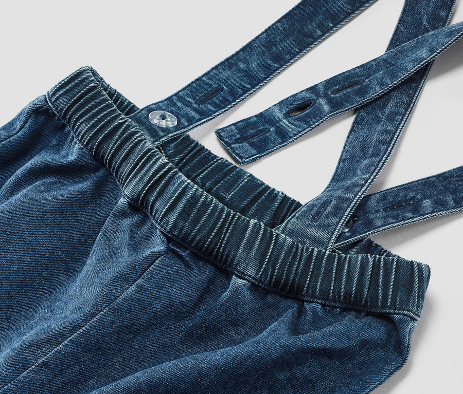 Gros plan sur un pantalon en twill pour bébé avec bretelles.