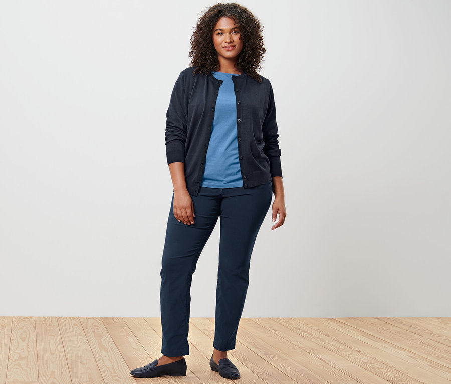 Une femme porte un cardigan en maille fine, un T-shirt et un pantalon.