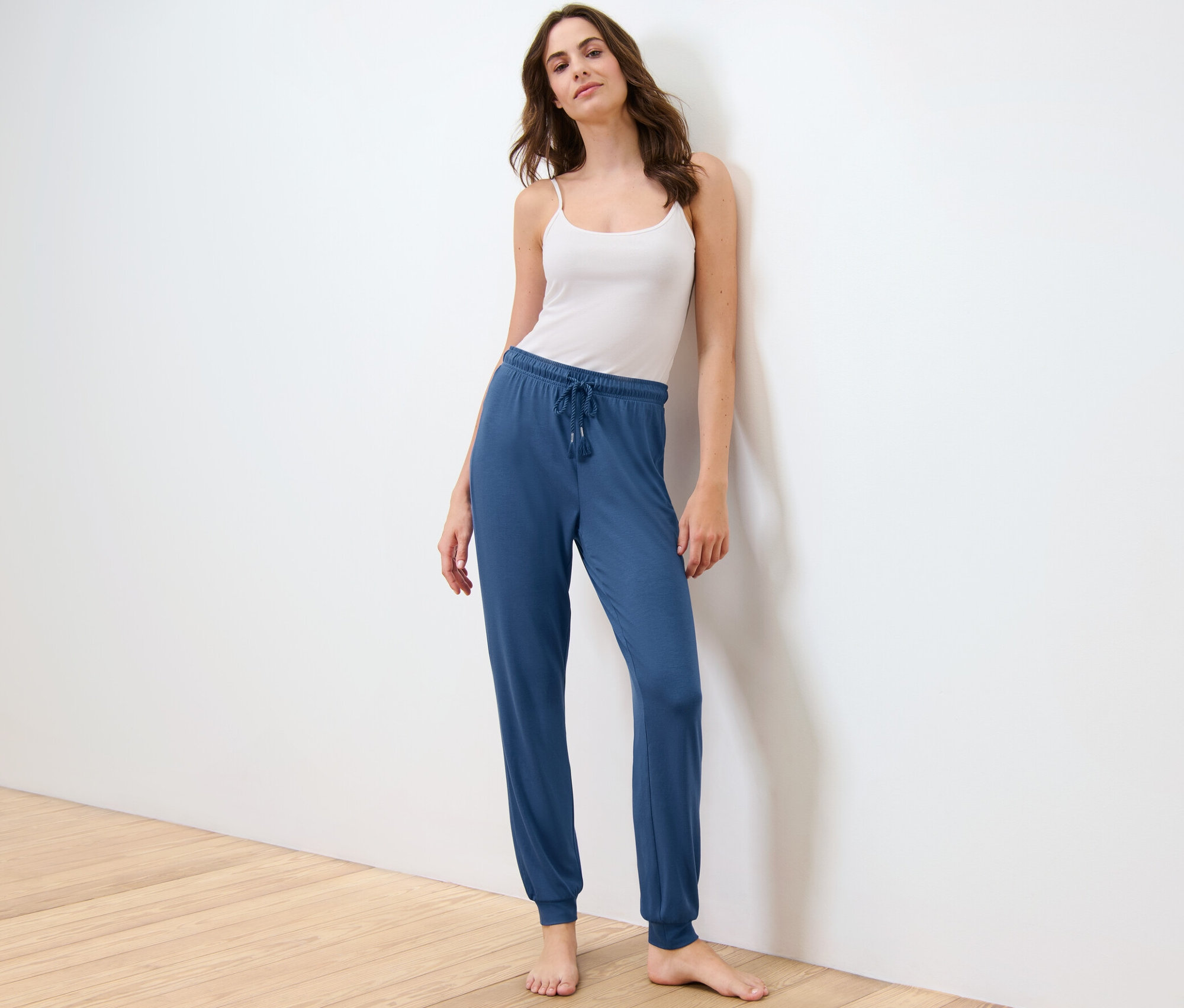 Femme posant en pantalon de pyjama et débardeur.