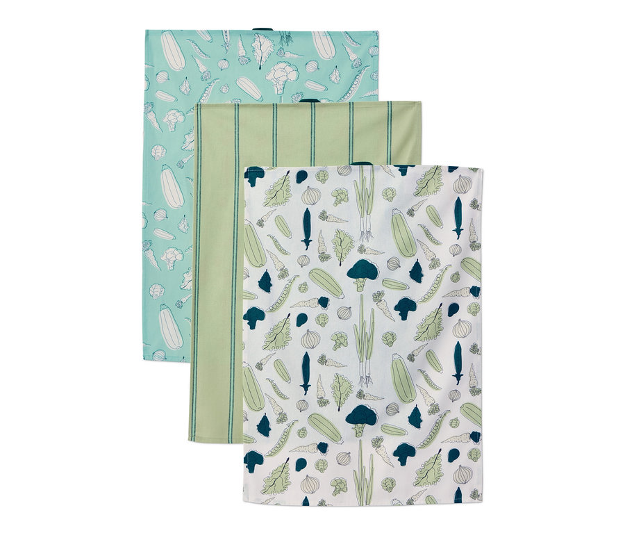 Trois linges de cuisine avec différents motifs. Un bleu clair avec des légumes, un vert rayé et un blanc avec des légumes.
