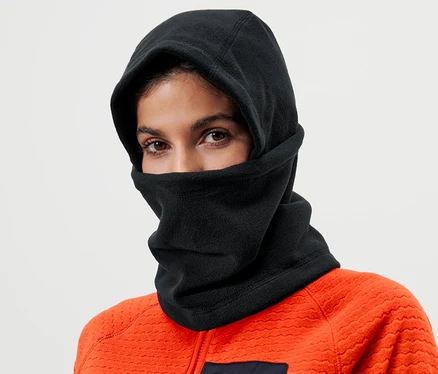 Une femme portant une cagoule noire en micropolaire et une veste orange.