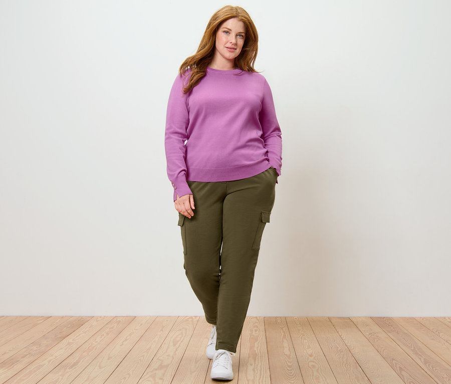 Femme posant en pull en maille fine et pantalon de jogging kaki à poches cargo.