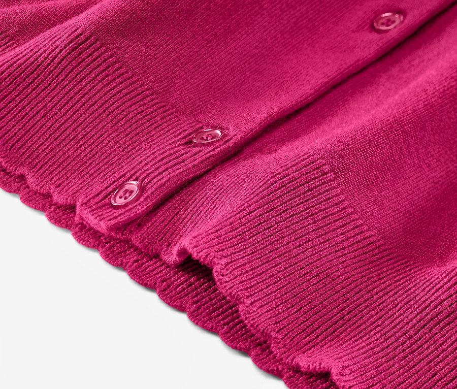 Gros plan sur un cardigan à maille fine avec bord ondulé.