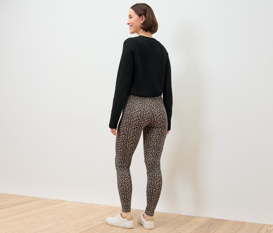 Femme portant un pull noir et un legging imprimé.